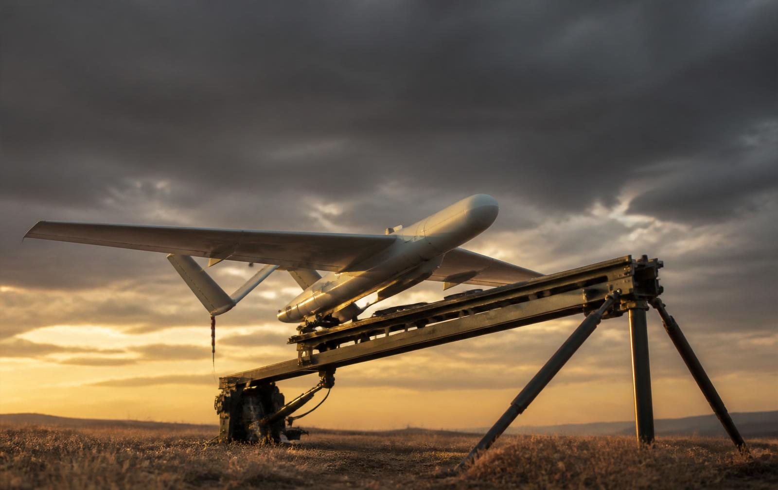 Interceptor drone on a launcher in a windswept field at dawn